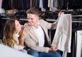 Joyous couple choosing new trousers in cloths store